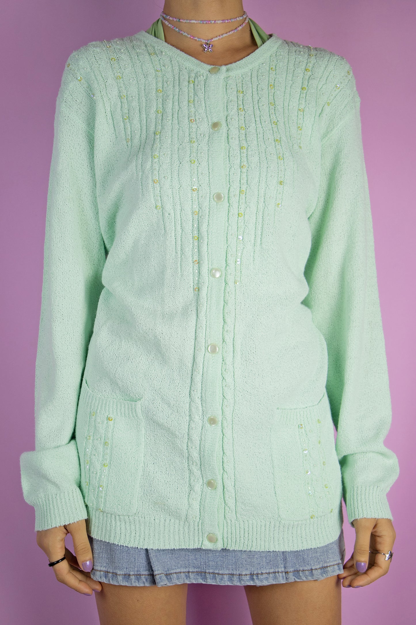 The Y2K Green Beaded Cardigan is a vintage light pastel mint green embellished cardigan with pockets and bead and sequin detail. Looks cute when worn oversized. Lovely retro 2000s knit sweater.