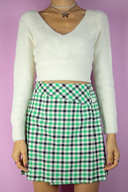 The Vintage 80s Check Pleated Mini Skirt is a green black and white plaid pleated wrap mini skirt with side button closure. Super cute classic preppy style 1980s mini skirt.
