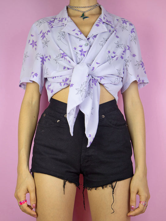 The Y2K Lilac Floral Print Blouse is a vintage 2000s boho cottagecore style light pastel purple short sleeve summer shirt with a collar and buttons.