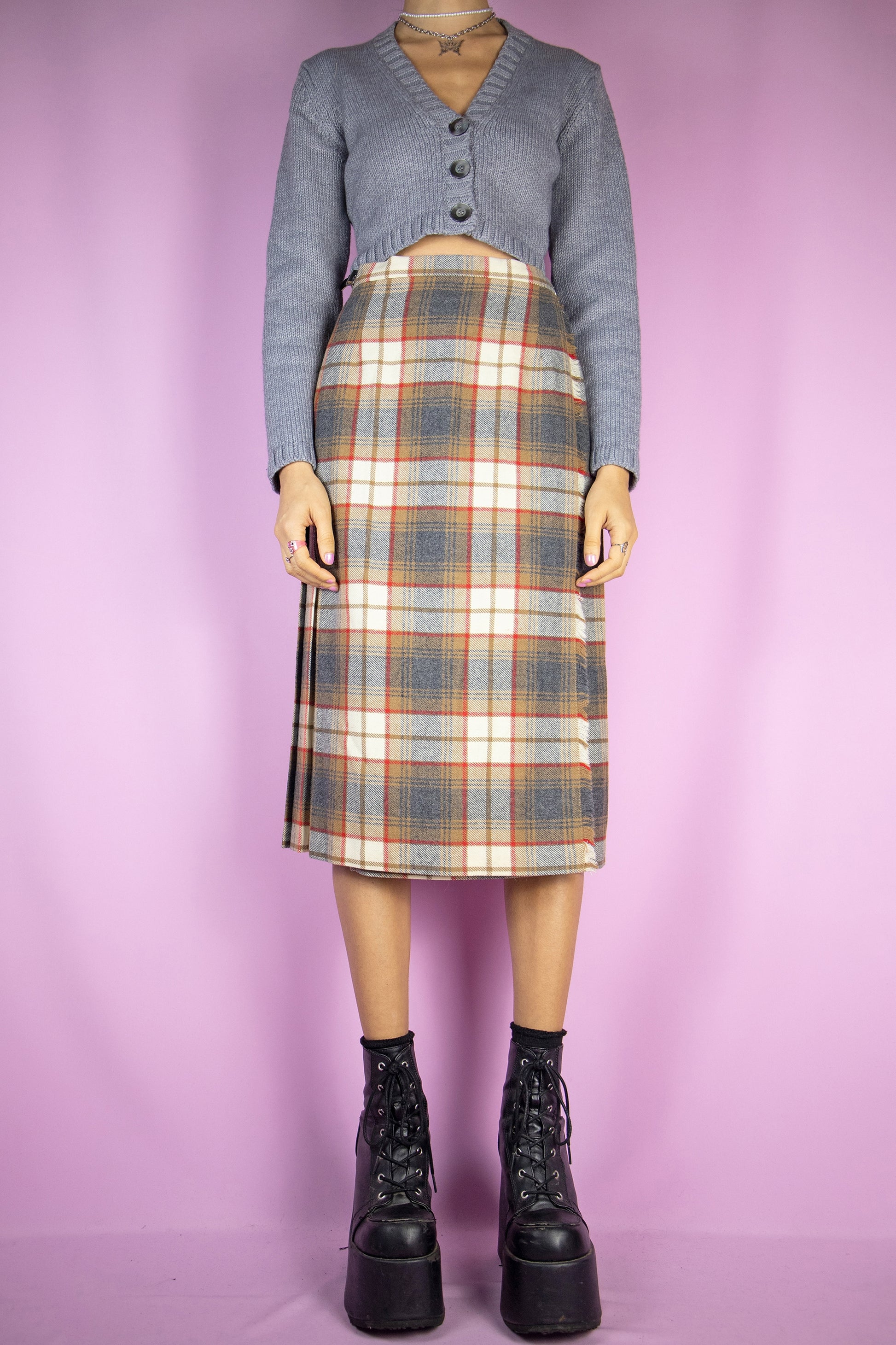 The Vintage 90s Wool Plaid Pleated Skirt is a brown multicolor check pleated wrap midi skirt with buckle closure made of virgin wool. Classic preppy tartan style 1990s winter skirt.