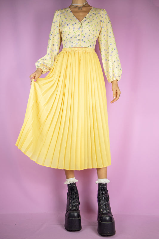 The Vintage 90s Yellow Pleated Midi Skirt is a long pleated yellow skirt with an elasticated waist. Classic preppy 1990s maxi skirt.