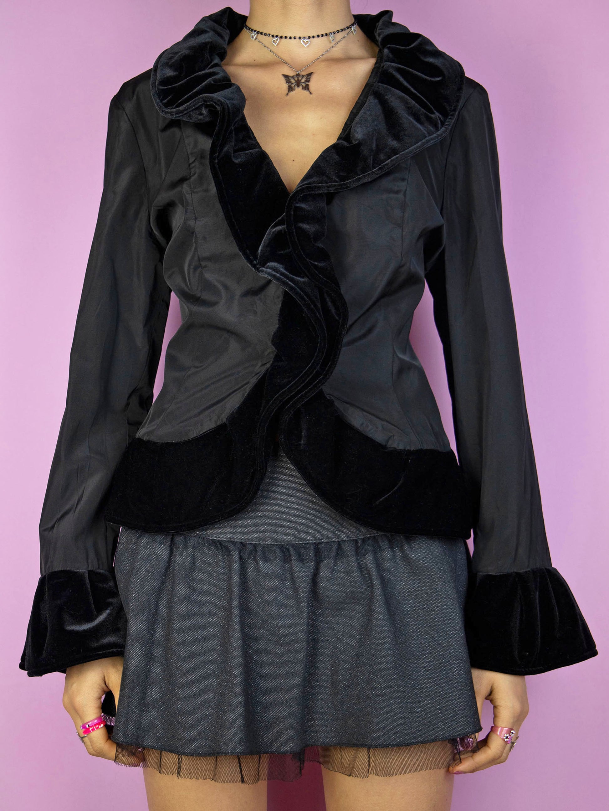 The Vintage 90s Black Ruffle Jacket is an elegant, romantic, whimsygoth-inspired statement piece, featuring velvet ruffle details and a front hook closure.