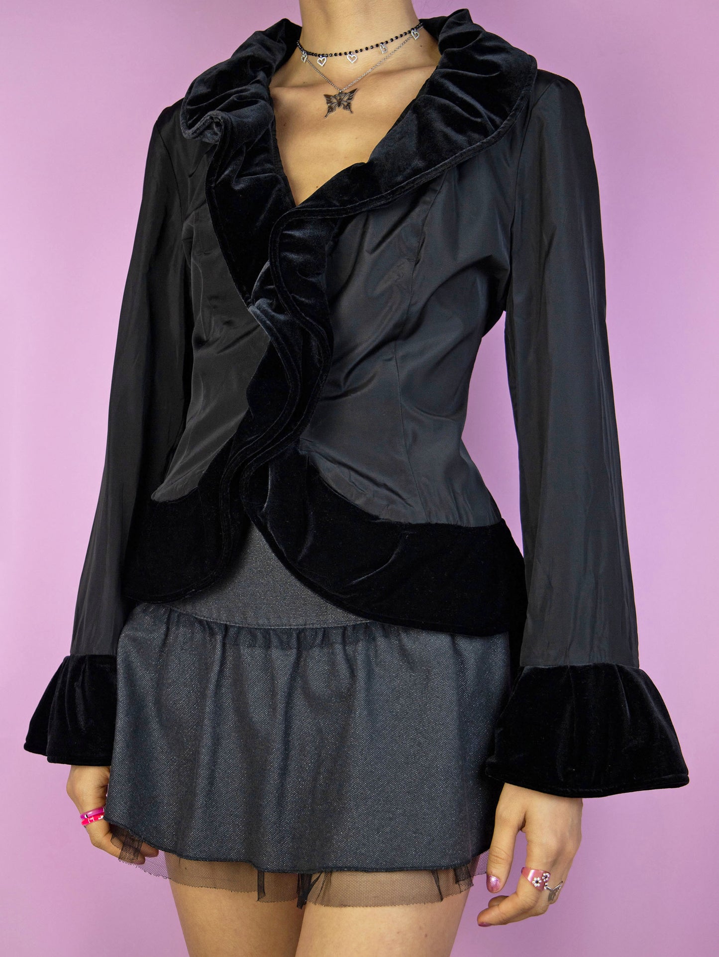 The Vintage 90s Black Ruffle Jacket is an elegant, romantic, whimsygoth-inspired statement piece, featuring velvet ruffle details and a front hook closure.