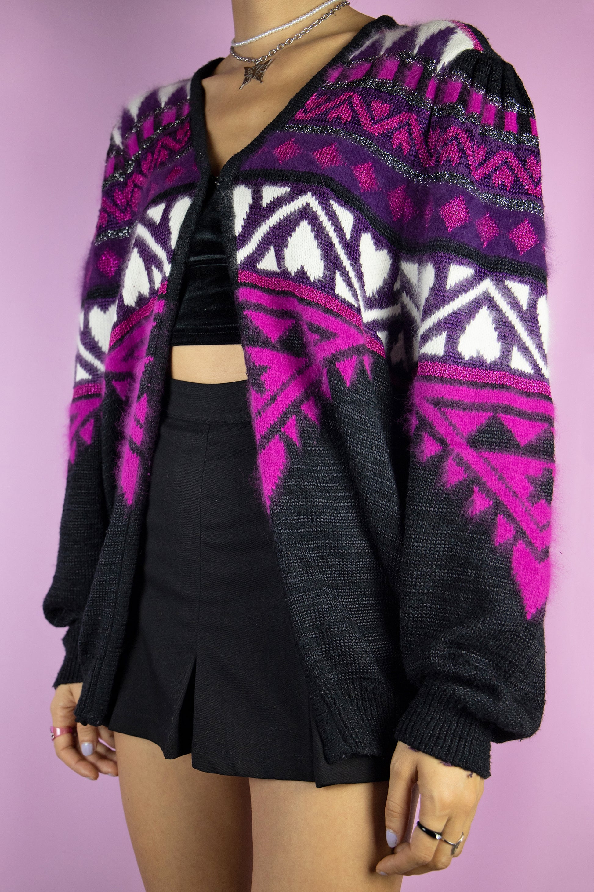 The Vintage 90s Black Puff Sleeve Cardigan is a black cardigan with purple, fuchsia and white abstract geometric pattern with puff sleeves and front hook closure. Looks cute when worn oversized. Lovely classic 1990s retro preppy style knit sweater.