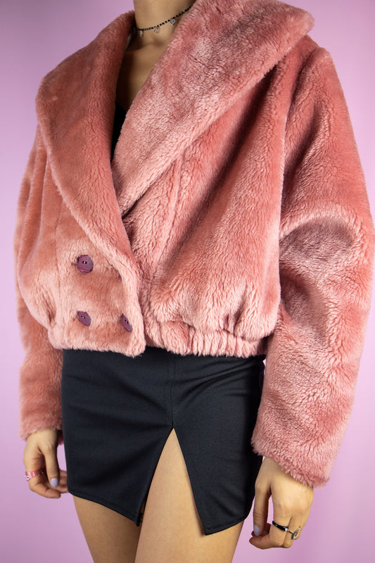 The Vintage 90s Pink Faux Fur Jacket is a pastel dusty pink faux fur jacket with a collar, buttons, pockets and elasticated waist. Romantic boho retro 1990s winter statement coat.