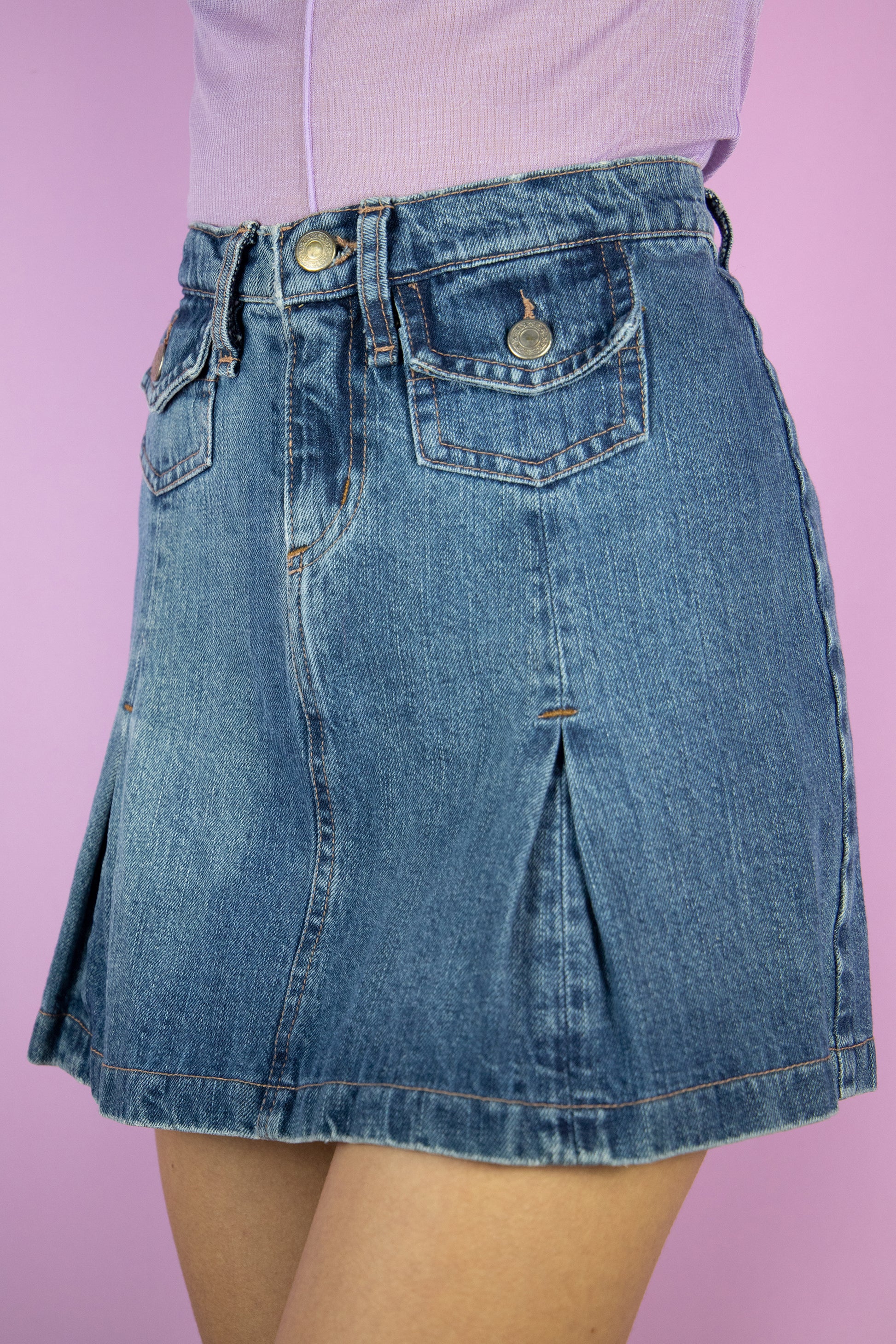 The Vintage 90s Denim Pleated Mini Skirt is a denim skirt with pleats and pockets. Super cute 2000s cyber mini skirt.