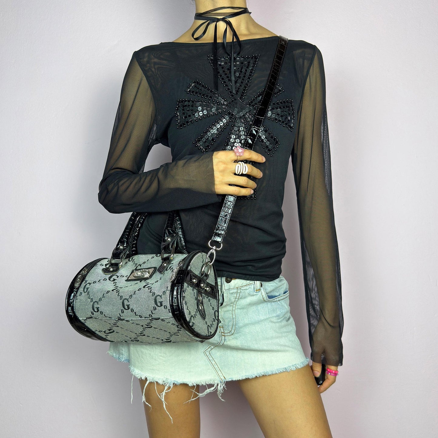 The Y2K Monogram Mini Duffel Bag is a stylish vintage 2000s accessory. Featuring a structured silhouette with an all-over monogram print, sleek black faux patent leather accents, and silver hardware. It includes dual top handles. adult world shop