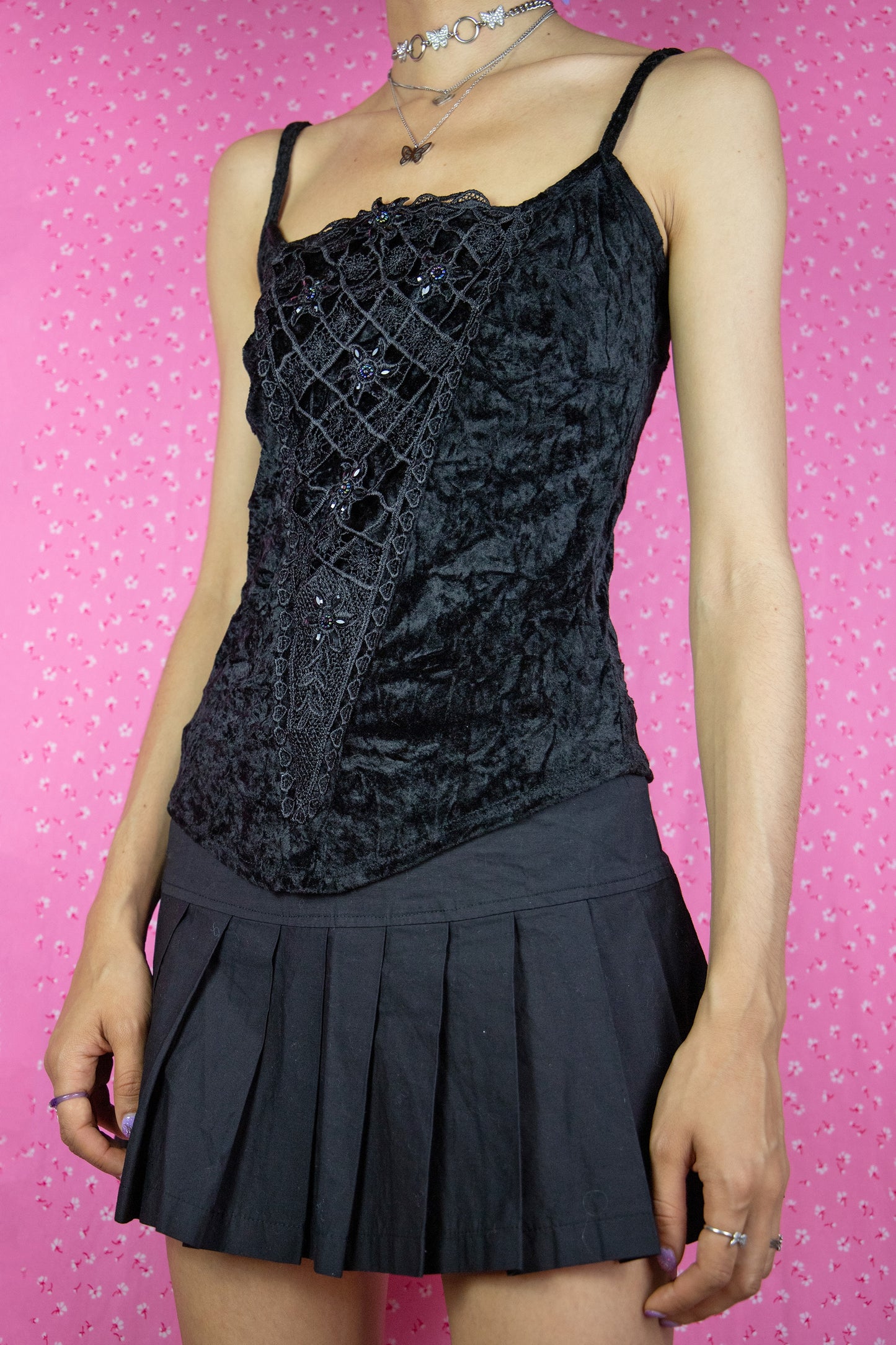 The Vintage Y2K Black Velvet Beaded Top is a crushed velvet black tank top with a stretchy fit, adorned with rhinestones and beads. This iconic top perfectly embodies the fairy grunge goth style of the 2000s.