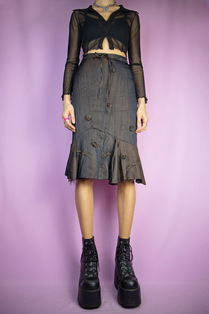 The Vintage 90’s Brown Ruffle Hem Skirt is an iridescent dark brown trumpet mini skirt with a charming ruffled hem, delicate appliqué details, a side zip closure, and laces that elegantly tie up the front. A delightful piece embodying fairy grunge goth fashion from the 1990s.